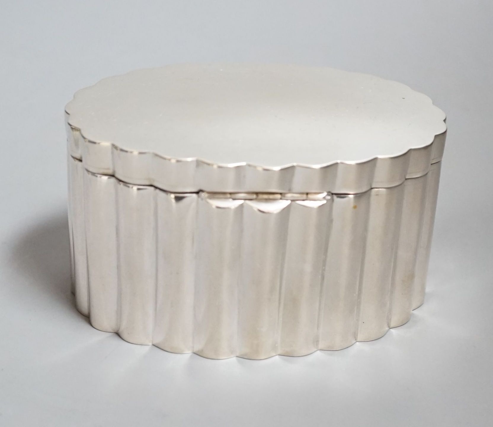 A fluted white metal oval sugar box, 13.3cm.